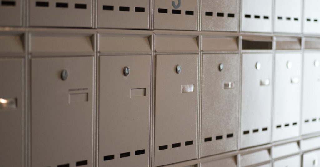 A series of secure steel mailboxes featuring strong locks and recessed hinges are aligned in a row.