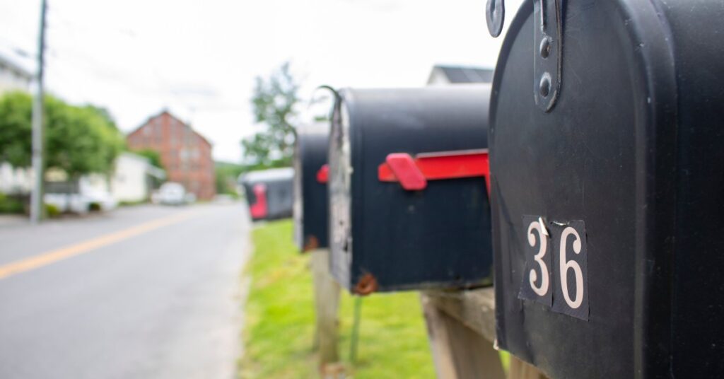 A row of black residential-style mailboxes along the street, with a closeup of a black mailbox numbered "36."