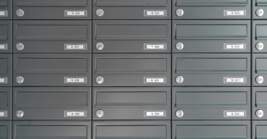 A close-up of individual mail slots incorporated into silver-colored cluster mailbox units with identifying numbers.