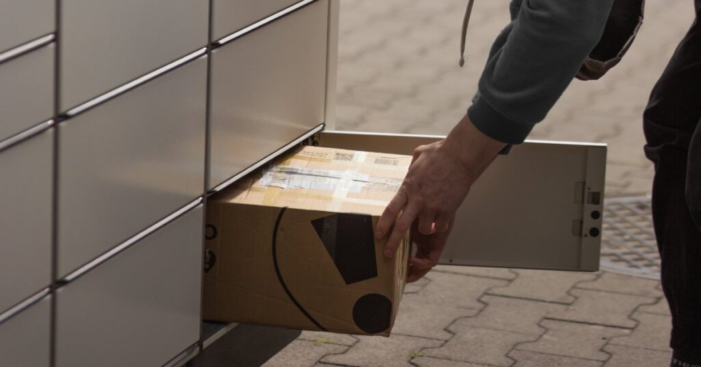 A man appears to receive a box from a cluster mailbox with a compartment large enough to store packages.