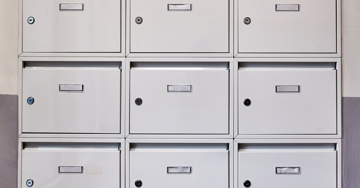 Nine individual units on a mailbox system mounted to a wall inside of a building. Each has an individual keyhole.