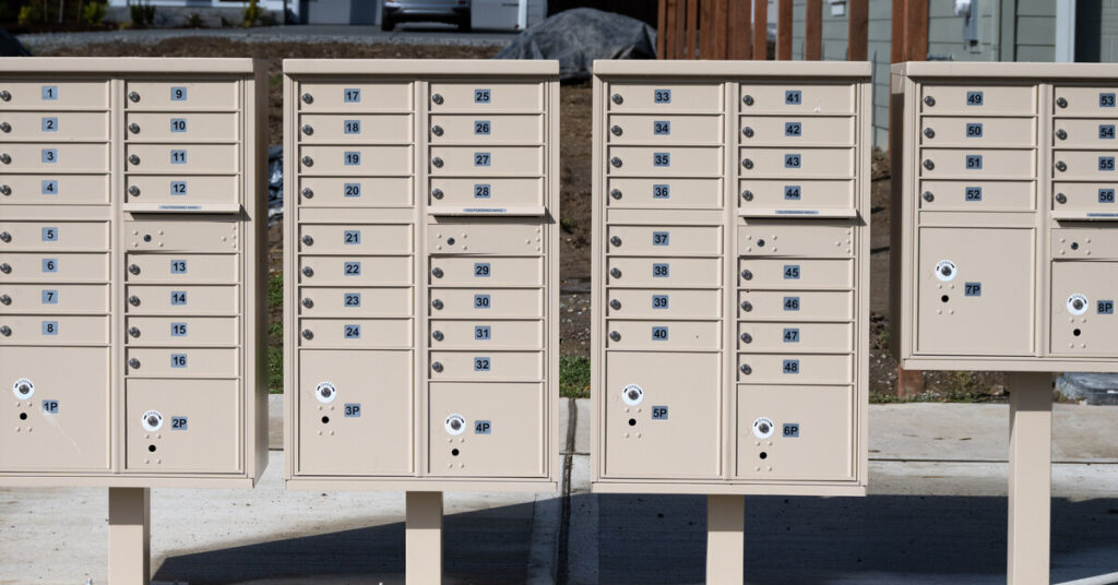 A large grouping of community mailboxes in a new residential neighborhood undergoing construction and development.