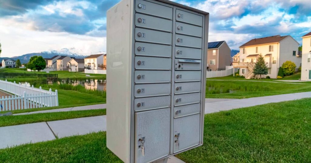 A cluster mailbox system installed on the sidewalk near a suburban neighborhood. The system includes two parcel lockers.