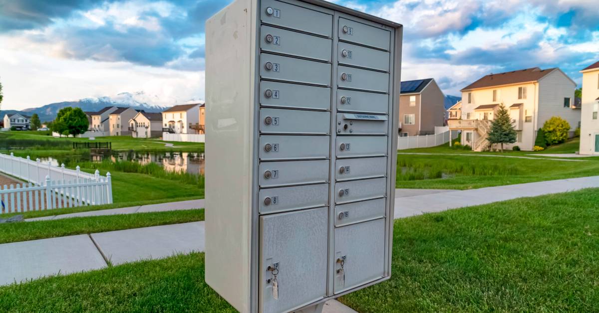 A cluster mailbox system installed on the sidewalk near a suburban neighborhood. The system includes two parcel lockers.