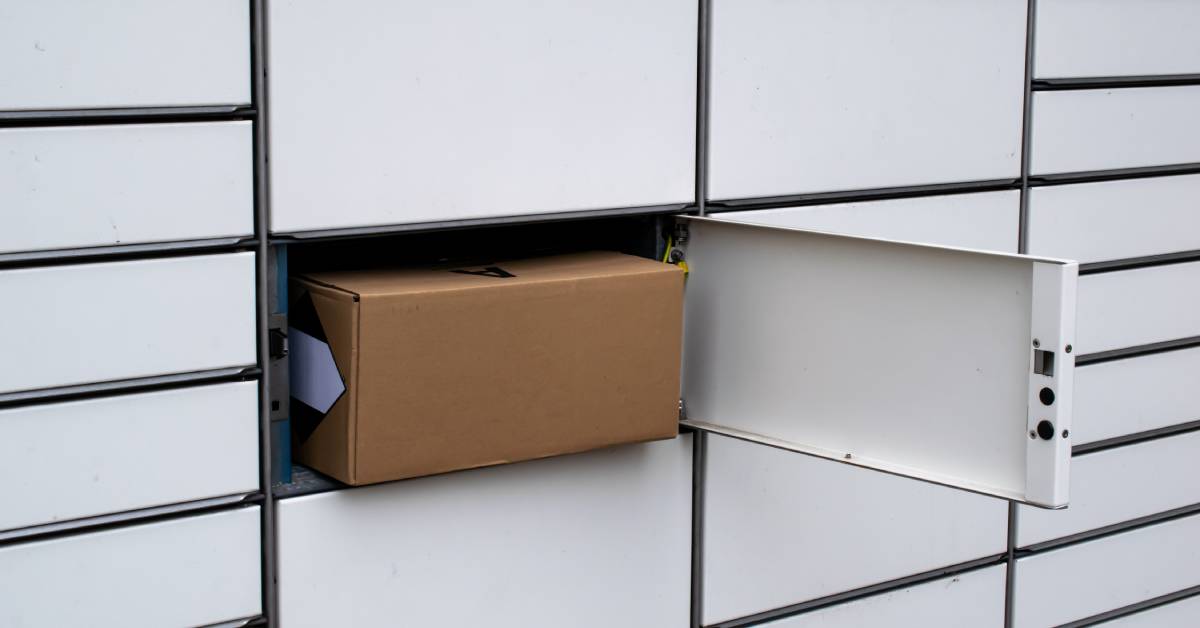 A brown carboard box sitting inside an opened individual parcel locker unit in a mail retrieval system.