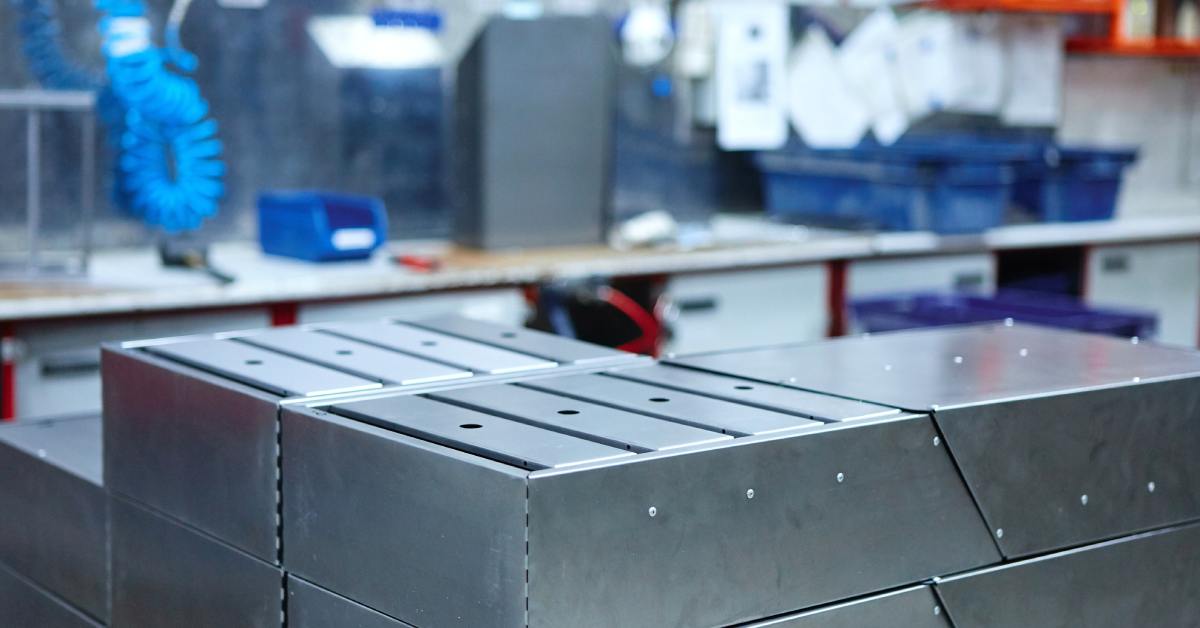 Several metal boxes with individual slots constructed into them lying in stacks on the surface of a table.