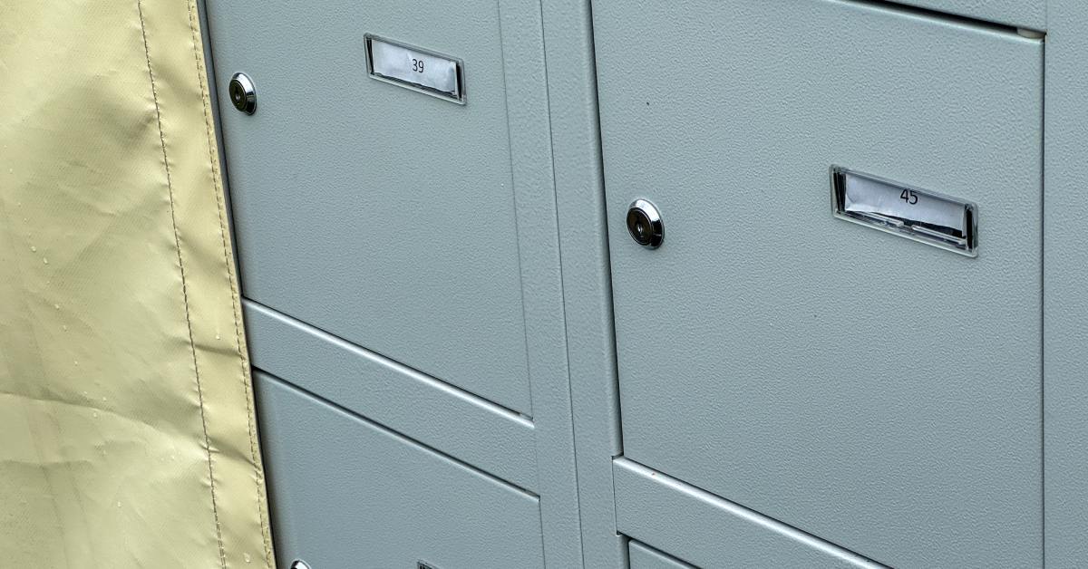 A light-colored protective shield positioned on the surface of postal boxes that have individual numbers and locks.